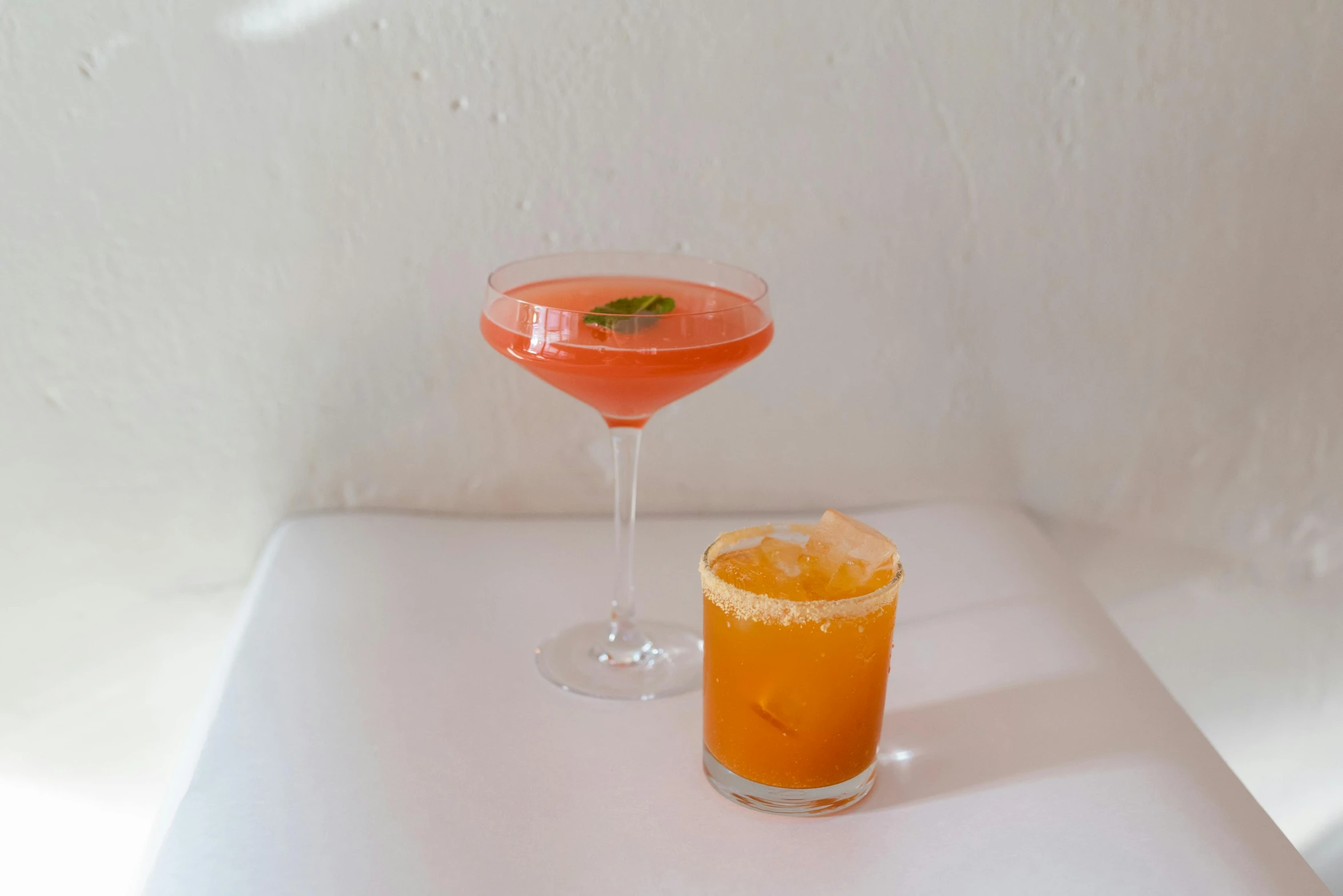 a couple of drinks sitting on top of a table, on a white table, vibrant orange, thumbnail, the hime cut