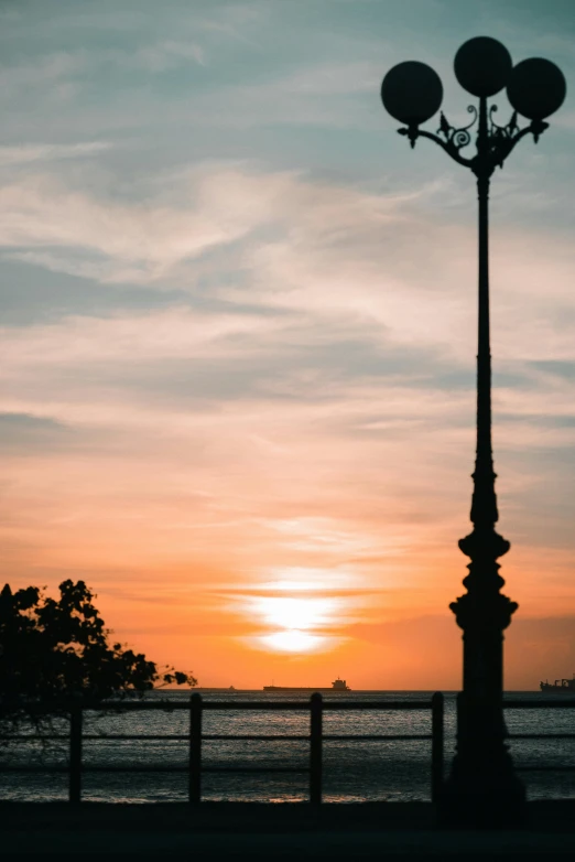 a street light sitting next to a body of water, pexels contest winner, sunsetting color, in savannah, singapore esplanade, sunny sky