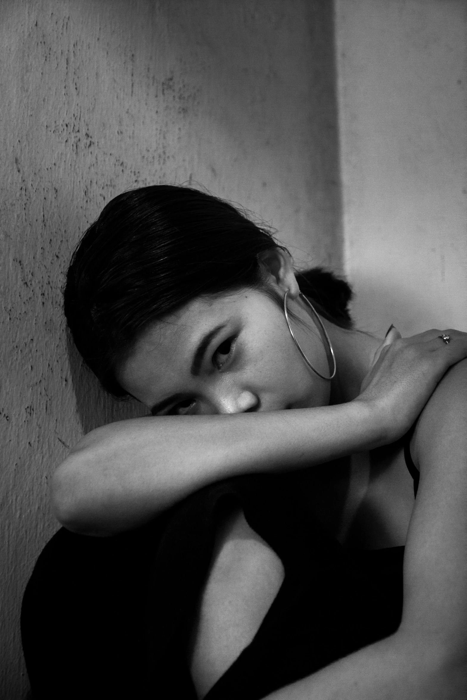 a black and white photo of a woman leaning against a wall, inspired by irakli nadar, flickr, realism, portrait of depressed teen, portrait of zendaya, still from a music video, crying tears of blood