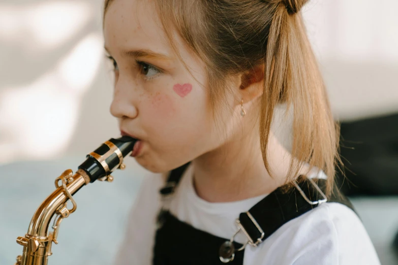 a little girl that is playing a saxophone, pexels contest winner, avatar image, enamel, profile image, carefully crafted