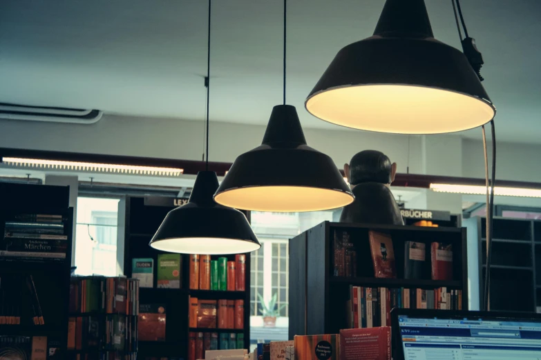 a laptop computer sitting on top of a wooden desk, by Jesper Knudsen, unsplash, light and space, interior of a library, light fixtures, shelves filled with tomes, retro lights