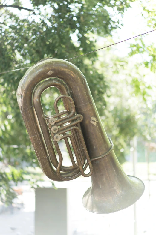 a brass instrument hanging from a clothes line, tuba knight, faded worn, up-close, made out of shiny white metal