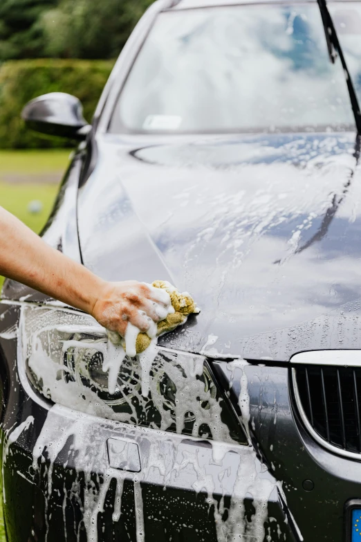 a man washing a car with a sponge, by An Gyeon, pexels contest winner, single body, black car, basic, as well as scratches