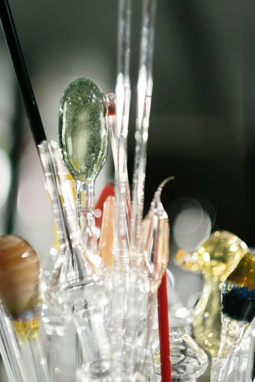 a bunch of glass spoons sitting on top of a table, inside a bar, ice needles, bubbles ”, brushes