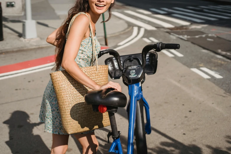 a woman standing next to a blue bike, bay area, background image, thumbnail, charging through city