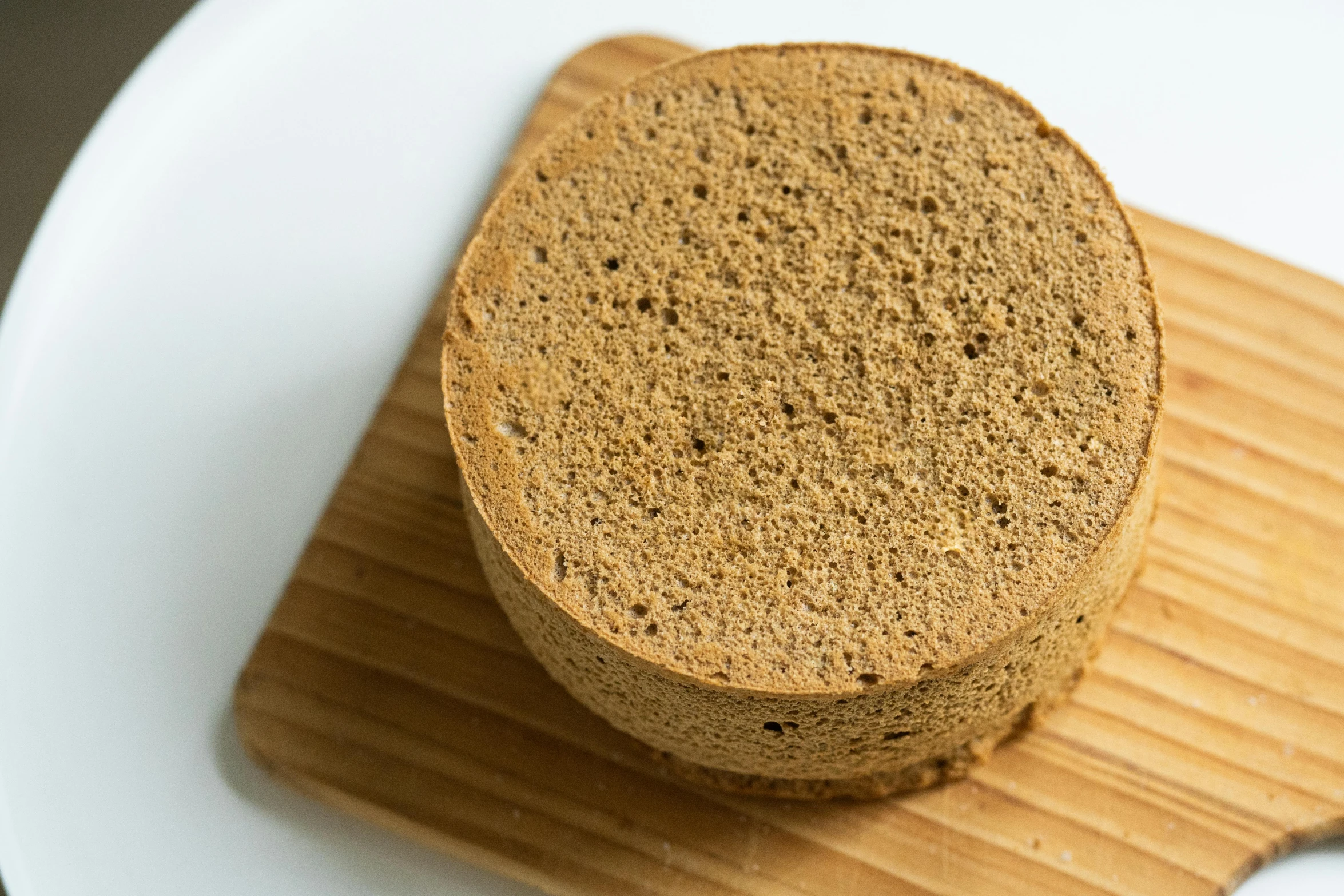 a piece of bread sitting on top of a cutting board, round form, product image, sponge, brown