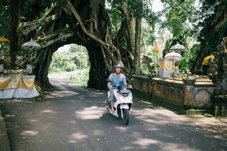 a man riding on the back of a white scooter, unsplash contest winner, archways made of lush greenery, white sarong, buttress tree roots, avatar image