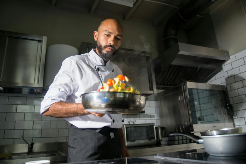 a man standing in a kitchen holding a pan of food, profile image, riyahd cassiem, fan favorite, chef table