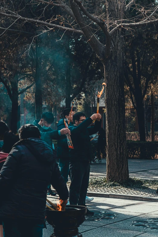 a group of people standing around a fire, a photo, by Yan Liben, pexels contest winner, graffiti, sunny day in a park, holding a sacrificial dagger, beijing, 🚿🗝📝