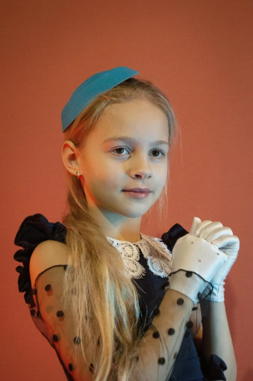 a young girl standing in front of a red wall, by Harriet Zeitlin, shutterstock, antipodeans, robotic prosthetic arm, white elbow gloves, little girl with blue hair, official photo