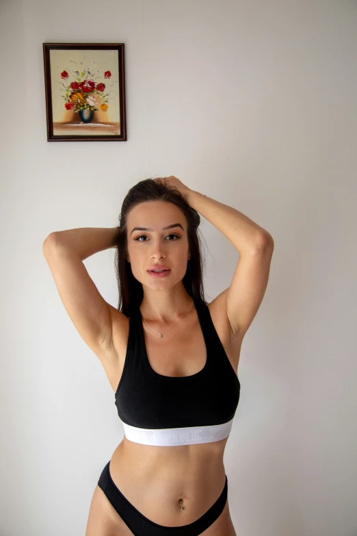 a woman in a black and white bikini posing for a picture, wearing a cropped black tank top, sport bra and shirt, in front of white back drop, head and shoulders shot