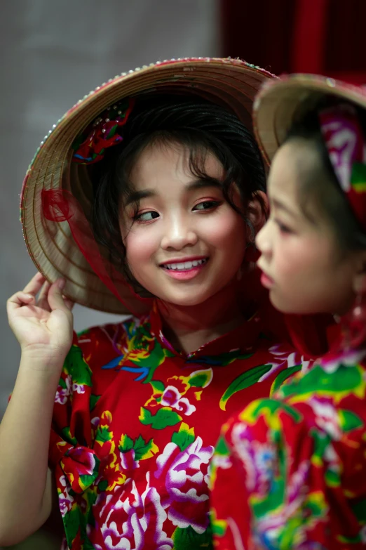 a couple of young girls standing next to each other, inspired by Ni Duan, flickr, red dress and hat, slide show, culture, close-up photo