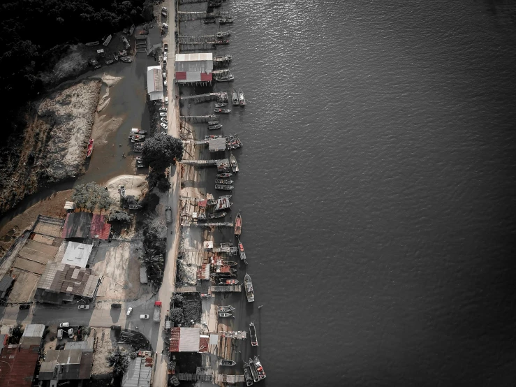 a group of boats sitting on top of a body of water, a black and white photo, by Basuki Abdullah, pexels contest winner, photorealism, drone view of a city, small settlements, red selective coloring, looking left