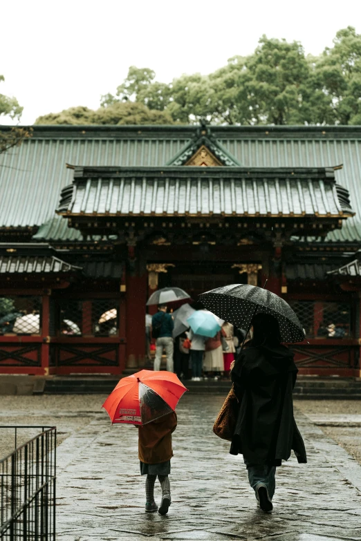 two people walking in the rain with umbrellas, a picture, inspired by Sesshū Tōyō, trending on unsplash, in front of a temple, ethnicity : japanese, square, color photo