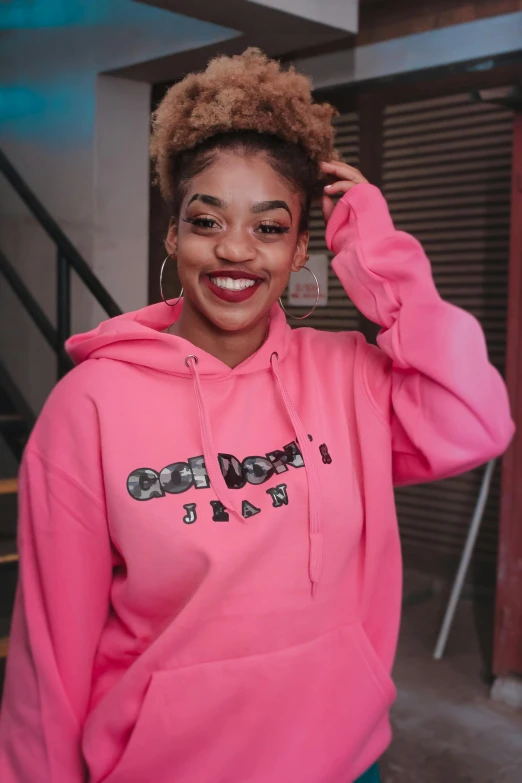 a woman in a pink hoodie poses for a picture, an album cover, by Dulah Marie Evans, trending on pexels, ashteroth, instagram story, oh yeah, lesbians