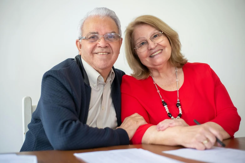 a man and a woman sitting at a table, document photo, smiling at camera, background image, carlos huante