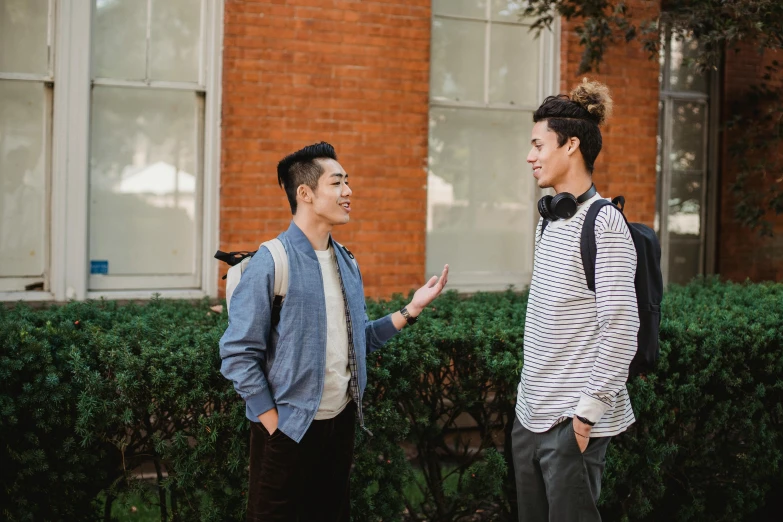 two men standing next to each other in front of a building, trending on pexels, college students, asian human, background image, nathan fowkes