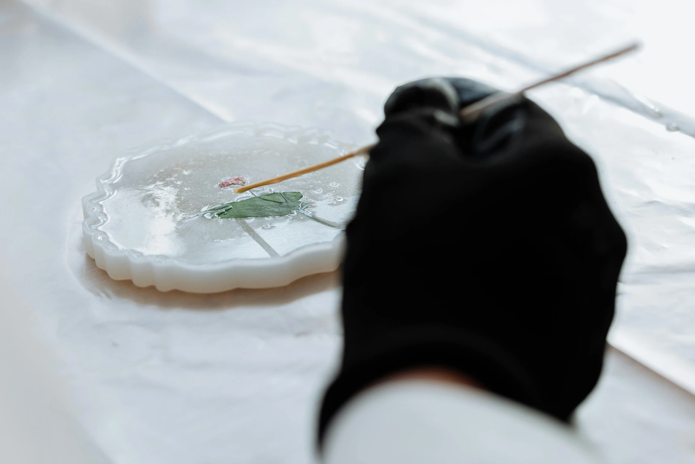 a person in black gloves painting on a white plate, inspired by Hans Holbein the Elder, unsplash, carved soap, glass paint, lily pad, animation