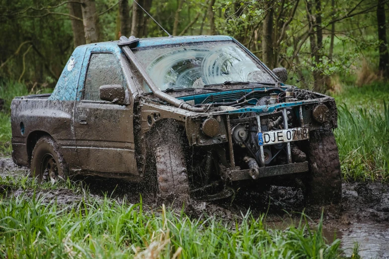 a truck that is sitting in the mud, woodland setting, blue, racing, very wet