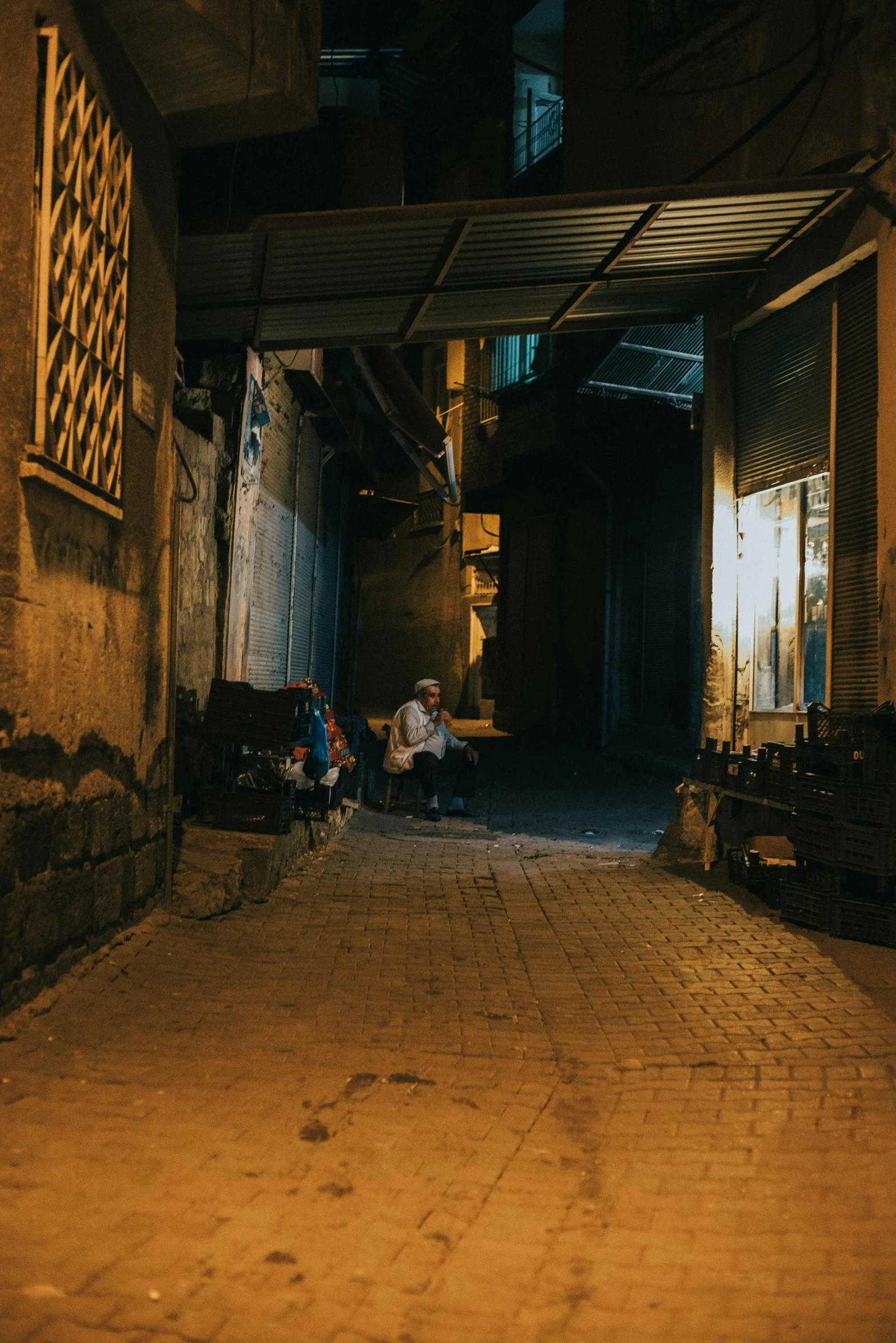 a couple of people that are sitting on a bench, by Youssef Howayek, les nabis, standing in a dark alleyway, people outside eating meals, sitting on the ground, in the early morning