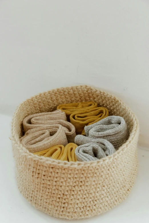 a basket filled with sweaters sitting on top of a table, by Nina Hamnett, unsplash, wearing wheat yellow gauze, foot wraps, crochet, close-up product photo