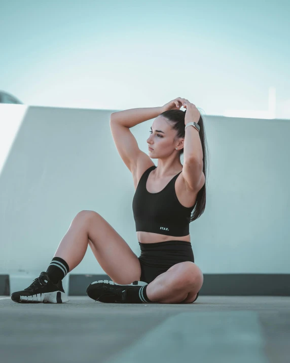 a woman sitting on the ground with her legs crossed, pexels contest winner, wearing a cropped black tank top, black ponytail, bra and shorts streetwear, profile image