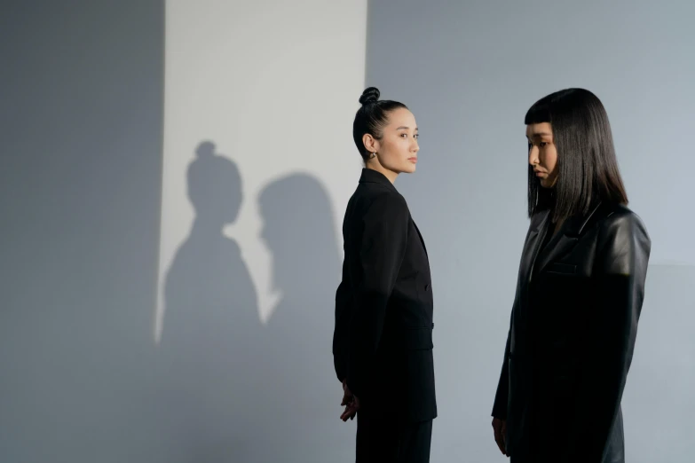 a couple of women standing next to each other, inspired by Wang Duo, pexels contest winner, minimalism, shadowy lighting, hito steyerl, yusuke murata and junji ito, wearing a black noble suit