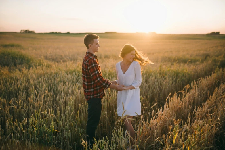 a man and woman holding hands in a wheat field, by Lee Loughridge, pexels contest winner, attractive girl, gentle lighting, flirting, lachlan bailey