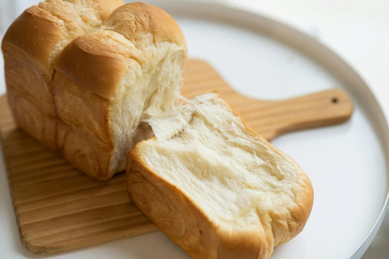 a loaf of bread sitting on top of a cutting board, aoi ogata, white sleeves, puffy, great quality