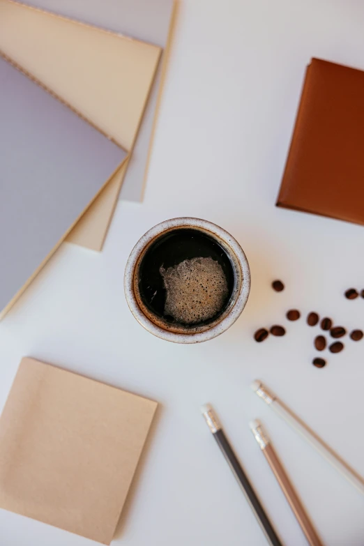 a laptop computer sitting on top of a table next to a cup of coffee, a still life, by Nicolette Macnamara, trending on unsplash, process art, black and brown colors, paper cup, art supplies, set against a white background