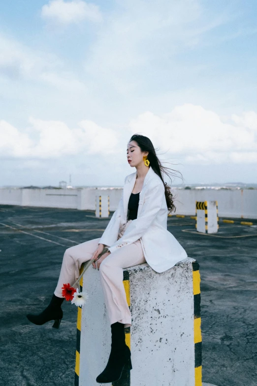 a woman sitting on a post in a parking lot, by Shang Xi, trending on pexels, wearing white suit, on rooftop, uniform off - white sky, fashionable woman