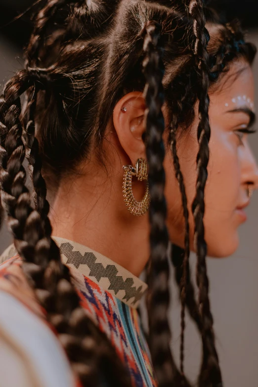 a close up of a person with long hair, by Nina Hamnett, trending on pexels, afrofuturism, braided hair loops, indian style, earrings, curated collection