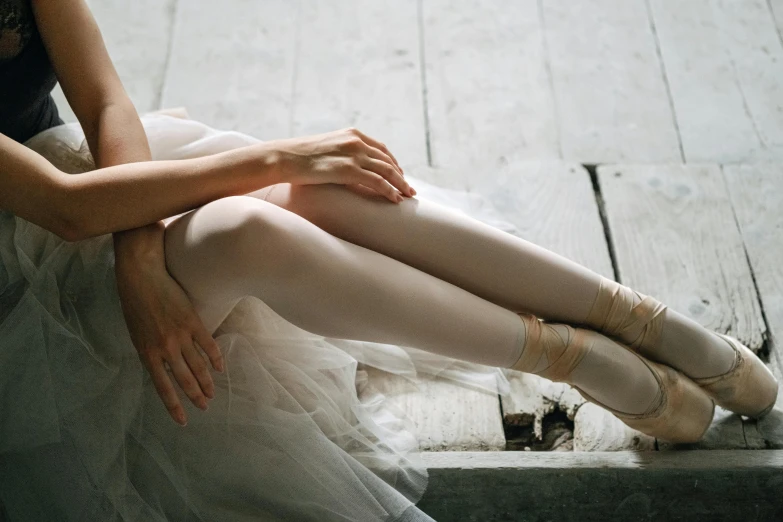 a close up of a person wearing ballet shoes, by Elizabeth Polunin, pexels contest winner, sitting on top a table, soft pale golden skin, white, pearlescent skin