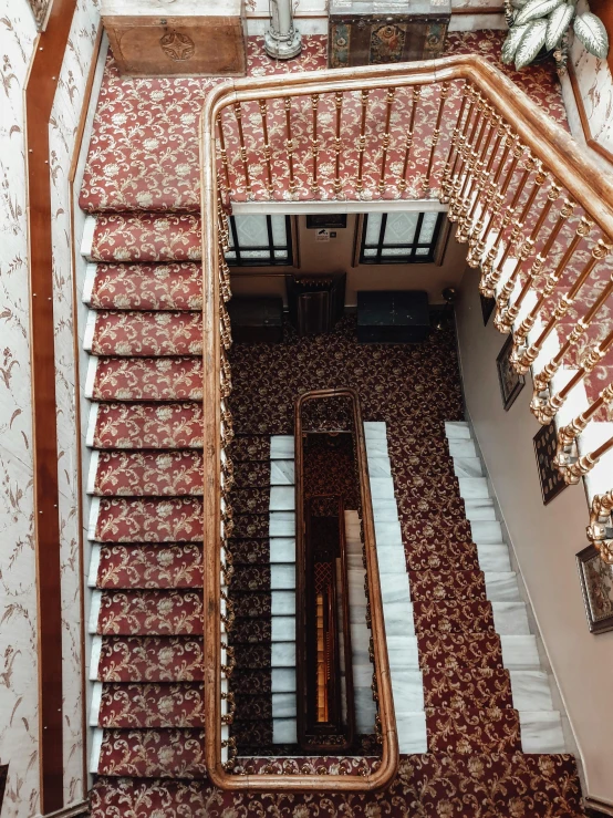 a staircase in a building with a clock on the wall, inspired by Vasily Surikov, unsplash, art nouveau, red carpeted floor, thumbnail, high angle view, iphone photo