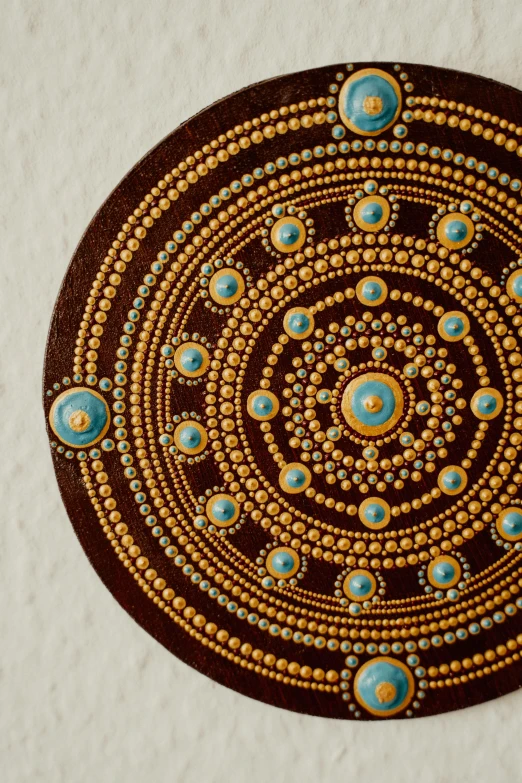 a close up of a piece of art on a wall, an ultrafine detailed painting, by Terese Nielsen, trending on unsplash, cloisonnism, mandala ornament, chocolate art, gold black and aqua colors, embedded with gemstones