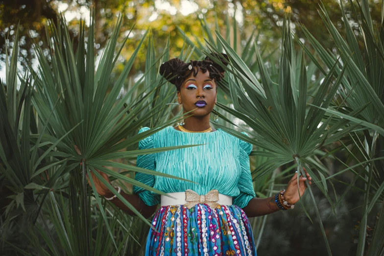 a woman standing in front of a palm tree, a portrait, by Lily Delissa Joseph, pexels contest winner, afrofuturism, teal skirt, in savannah, woman made of plants, wearing authentic attire