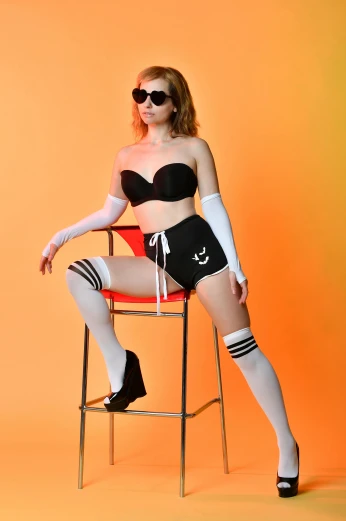 a woman sitting on top of a red chair, an album cover, inspired by Elsa Bleda, unsplash, dada, wearing black shorts, model エリサヘス s from acquamodels, wearing spandex bikini, shades