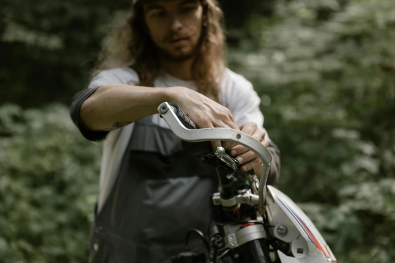 a man that is standing next to a motorcycle, unsplash, process art, curved blades on each hand, mountain bike helmet, grey, levers