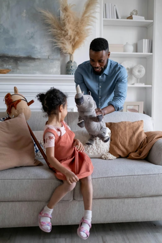 a man and a little girl sitting on a couch, stuffed animal, playing, smooth clean surfaces, home display