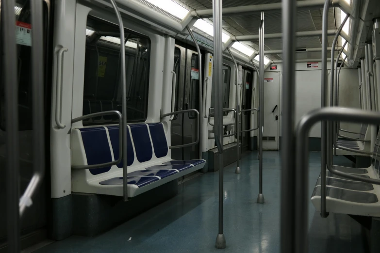 the inside of a subway car with blue seats, by Alejandro Obregón, slight overcast lighting, covid, bay area, two crutches near bench