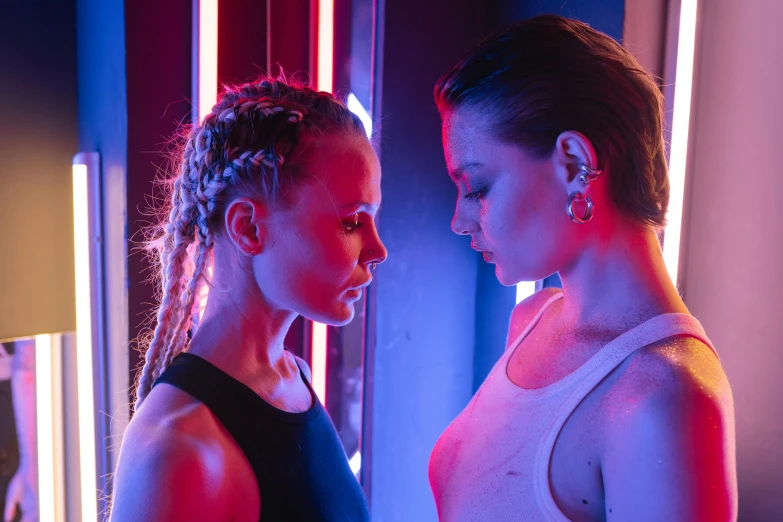 a couple of women standing next to each other, inspired by Nan Goldin, pexels contest winner, bauhaus, red and blue neon, sweaty 4 k, portrait sophie mudd, facing each other