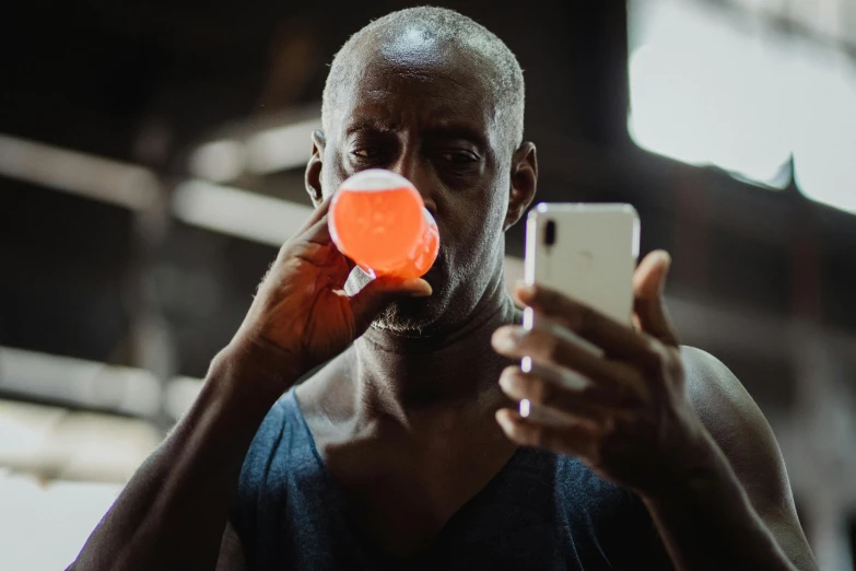 a close up of a person holding a cell phone, pexels contest winner, happening, transhumanist hydration, man is with black skin, blowing bubblegum, digital pong screen