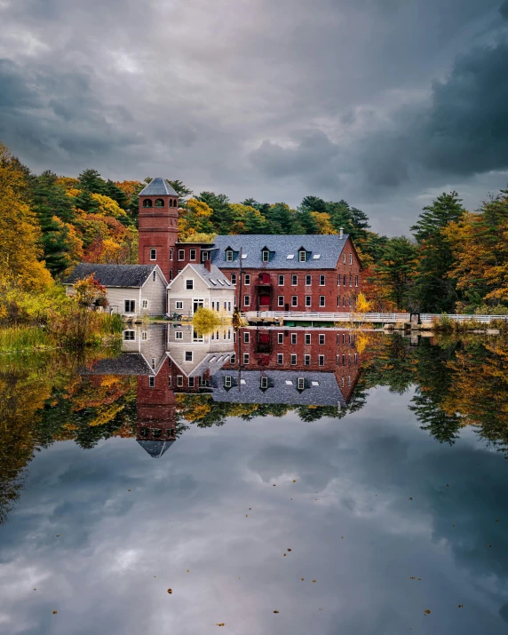 a red brick building sitting on top of a lake, pexels contest winner, hudson river school, mill, spooky photo, swedish houses, muted fall colors
