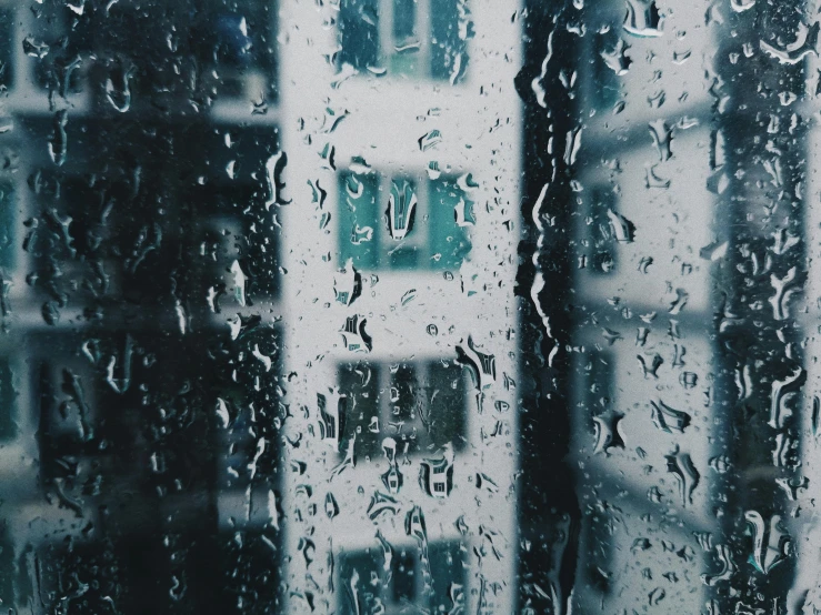 a window covered in rain next to a tall building, inspired by Elsa Bleda, pexels contest winner, shades of blue and grey, glass houses, background image, crying softly and humbly