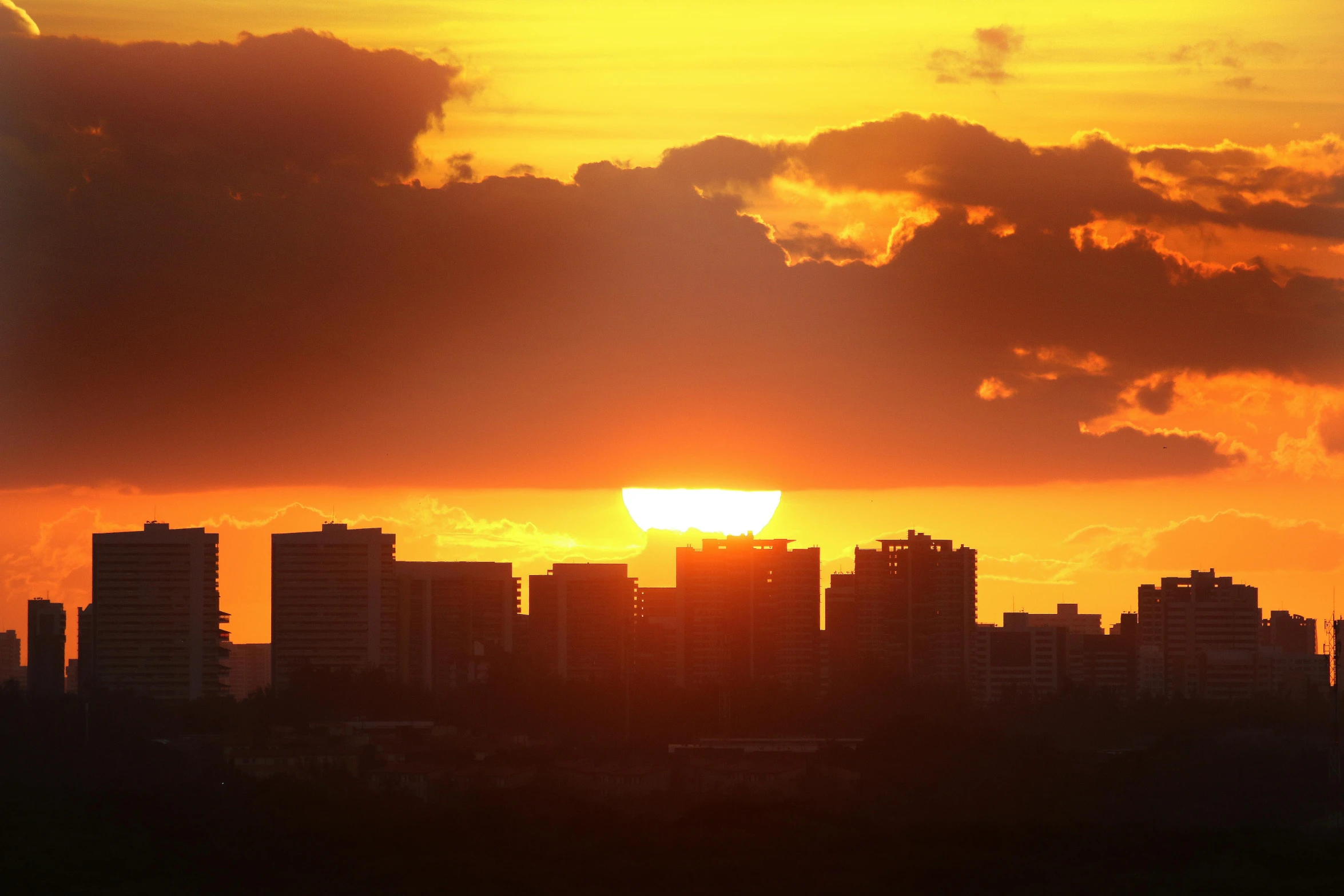 the sun is setting over the city skyline, by Dan Luvisi, pexels contest winner, minimalism, puerto rico, zoomed out shot, getty images, heat waves