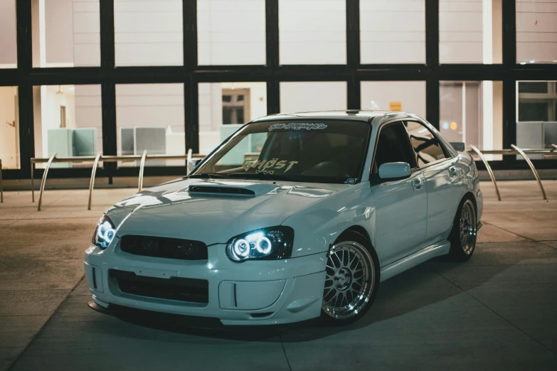 a white car parked in front of a building, inspired by An Gyeon, unsplash, hurufiyya, with cool headlights, subaru, 2000s photo, indoor picture