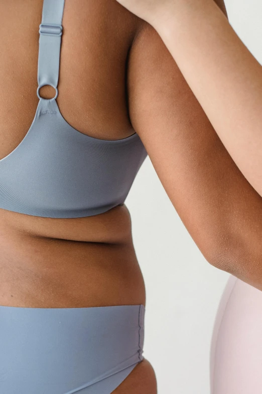 a woman in a blue bikini is brushing her teeth, by Matija Jama, unsplash, renaissance, detailed sports bra, folds of belly flab, on grey background, high-body detail