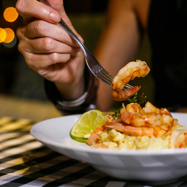 a close up of a plate of food with a fork, pexels contest winner, shrimp, night life, hand on table, daily specials