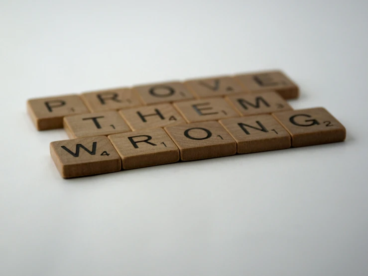 a couple of scrabbles sitting on top of each other, by Robbie Trevino, pexels contest winner, ironic, background image, perfect letters, the right from wrong