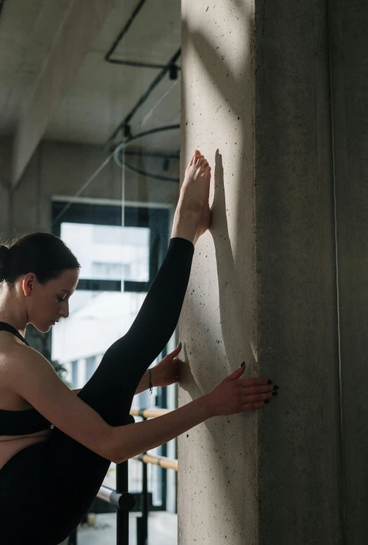 a woman in a black leo leo leo leo leo leo leo leo leo leo leo leo leo, inspired by Elizabeth Polunin, trending on pexels, arabesque, leaning on the wall, working out, cracks, in a gym